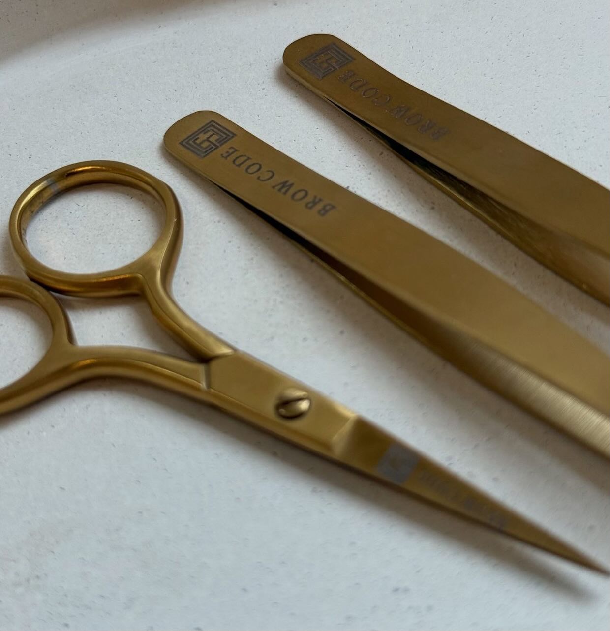 Gouden Brow Code schaar en pincetten op de werktafel